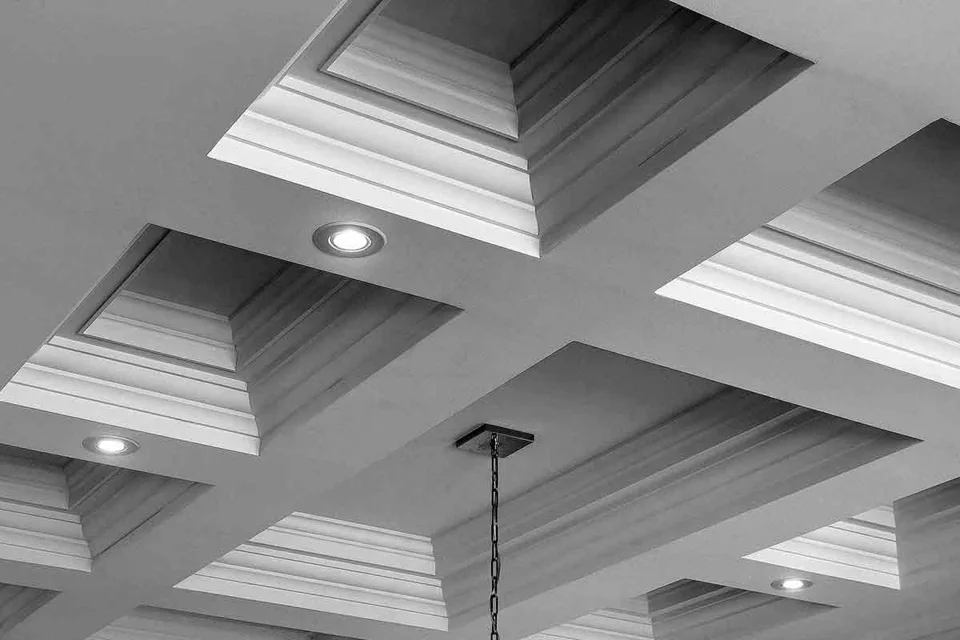 Quadrillage de plafond à caissons avec moulures superposées et luminaires encastrés.