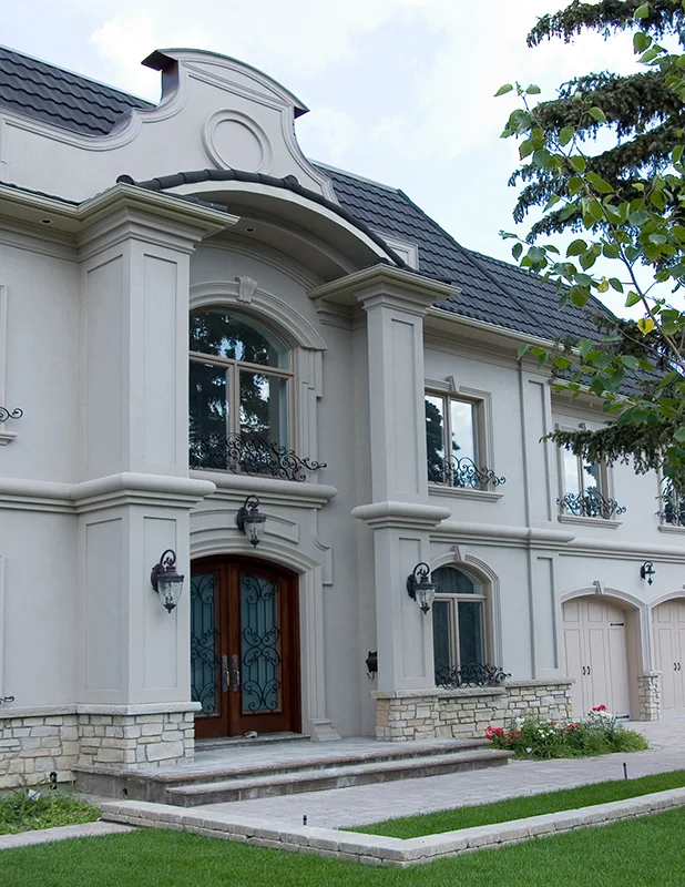 Maison blanche avec encadrements décoratifs et toiture centrale courbée.