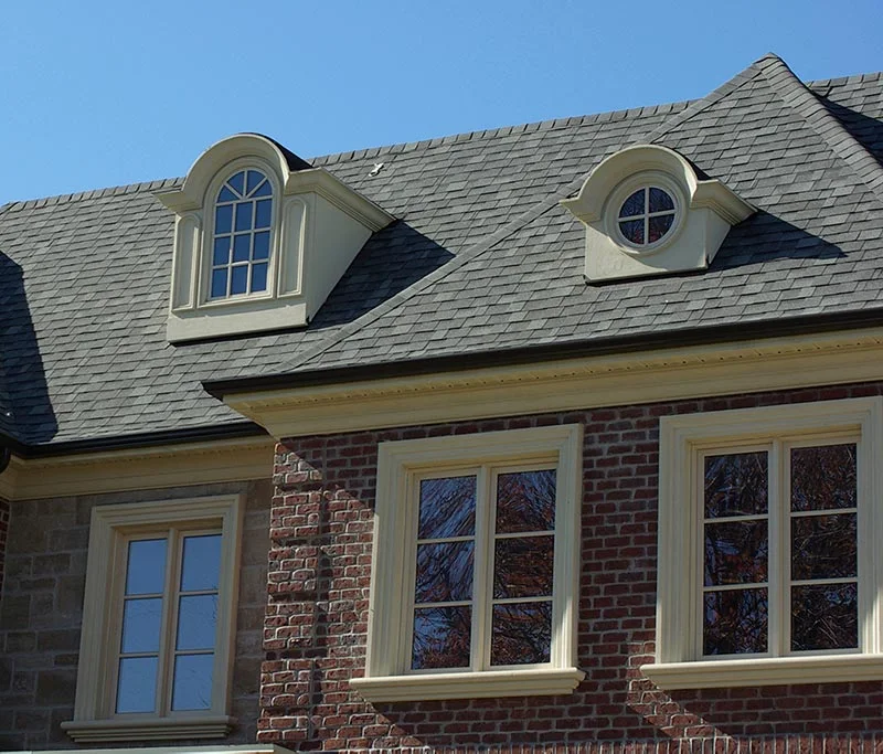 Façade en brique avec encadrements pâles et deux lucarnes.