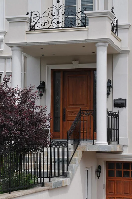 Colonnes encadrant une porte sous un balcon.