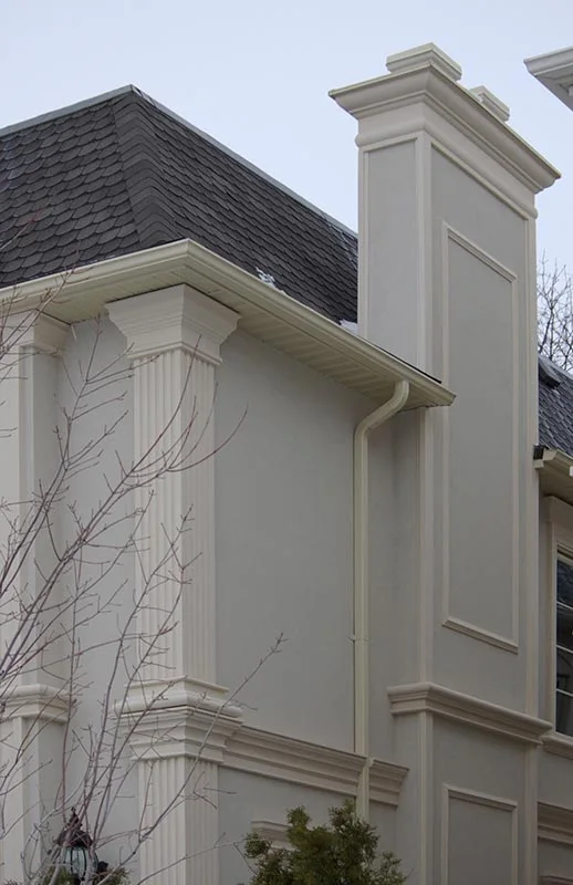 Pilastre rectangulaire près d’un mur extérieur pâle.