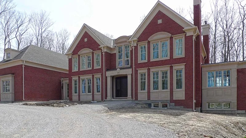 Maison en brique rouge avec encadrements blancs, pierres d’angle et entrée cintrée.